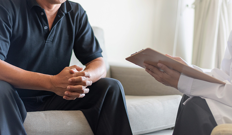 Man with pad talking to another in a consultation.